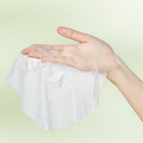 Hand holding an unfolded Mixsoon Centella sheet mask against a green background
